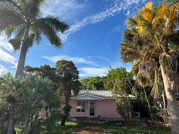 a front view of a house with a yard and palm trees