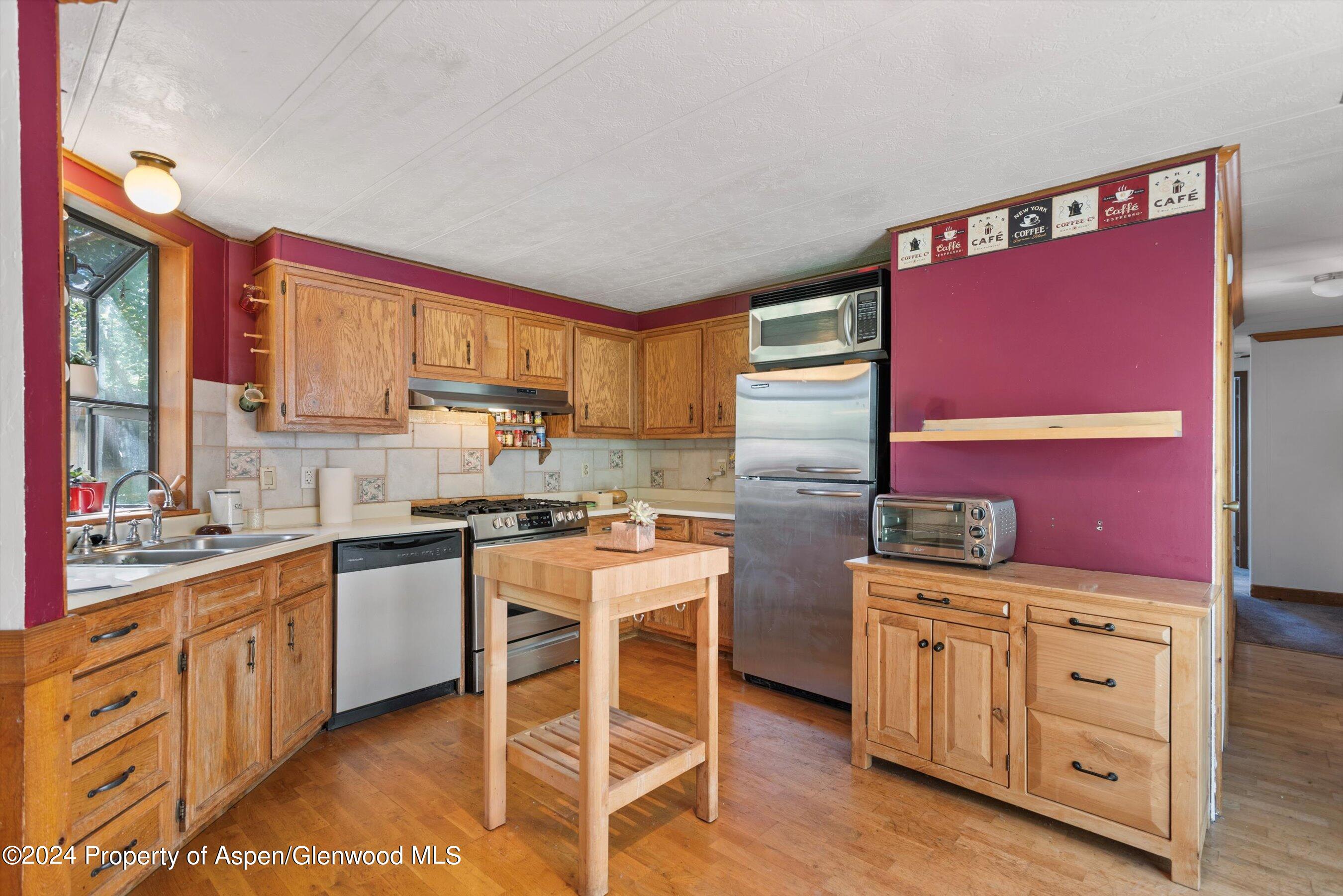 40 Aspen Village Road Aspen, CO 81611 - Photo 2 of 19 a kitchen with stainless steel appliances kitchen island granite countertop a stove top oven a sink a dining table and chairs with wooden floor