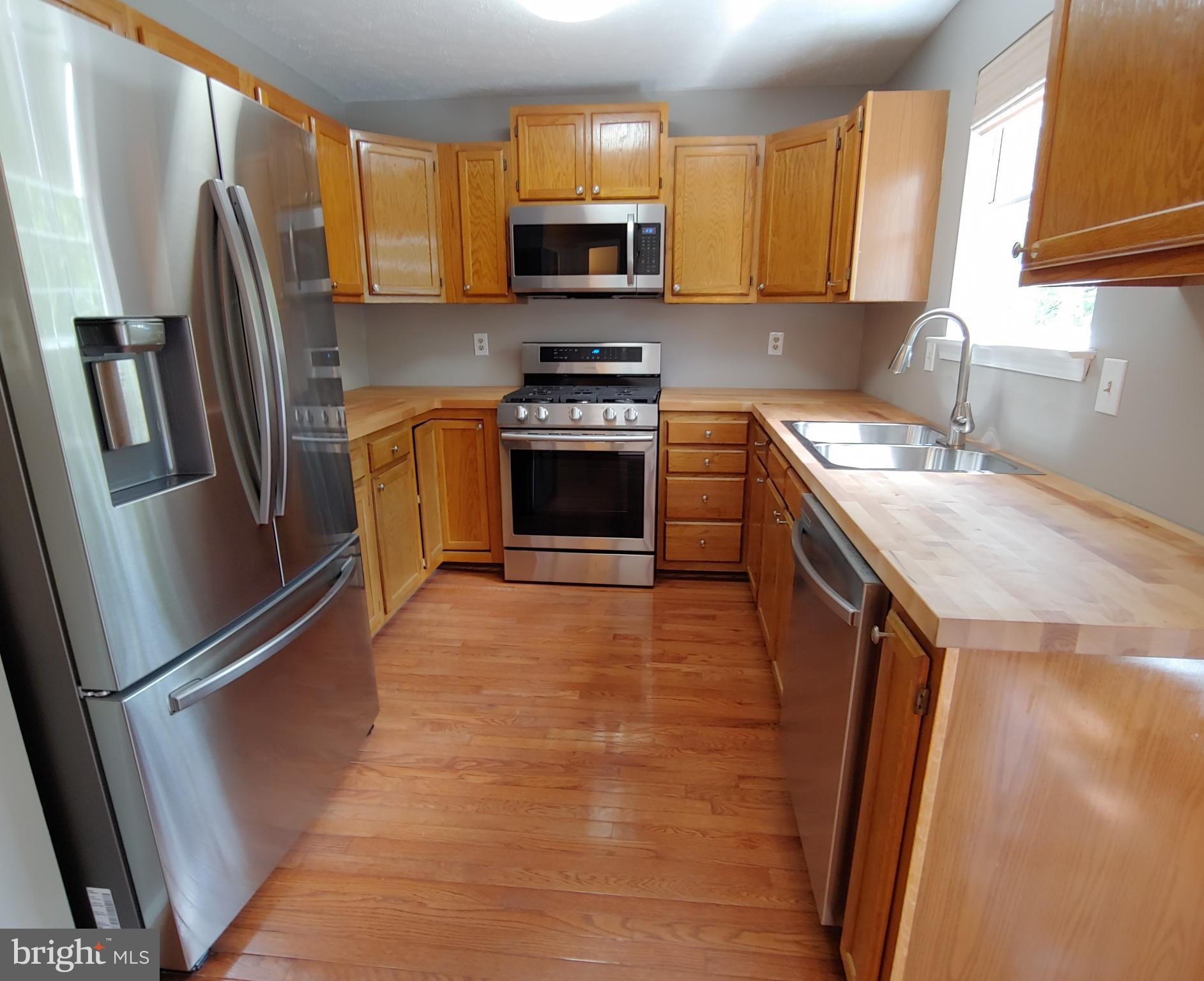 6010 Grenfell Loop Bowie, MD 20720 - Photo 13 of 32 a kitchen with refrigerator a microwave a sink and cabinets