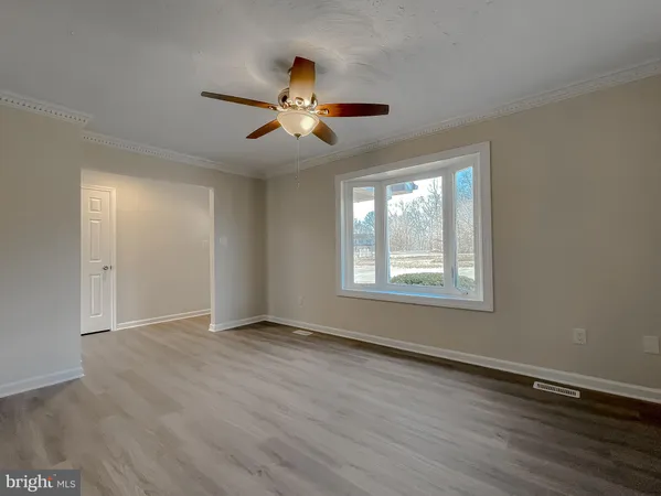 a view of an empty room with wooden floor and a window