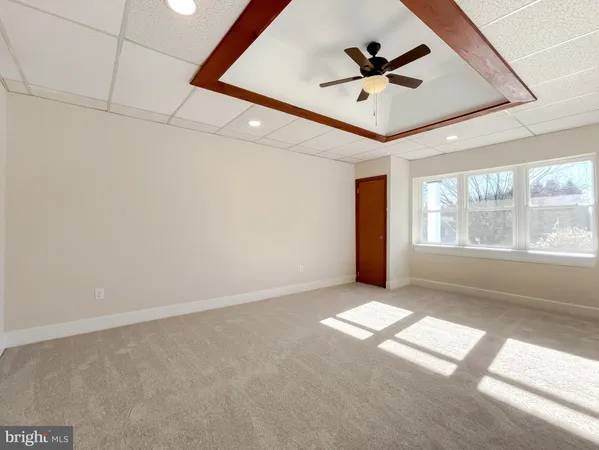 an empty room with windows and ceiling fan