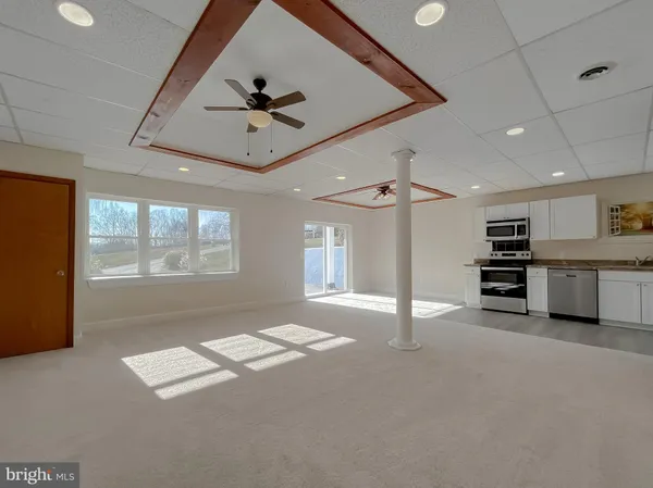 a view of an empty room with a window and kitchen view