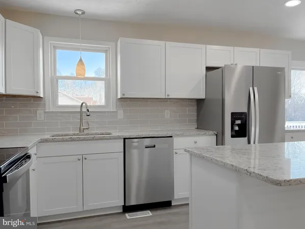 a kitchen with stainless steel appliances granite countertop a sink a refrigerator and a granite counter tops