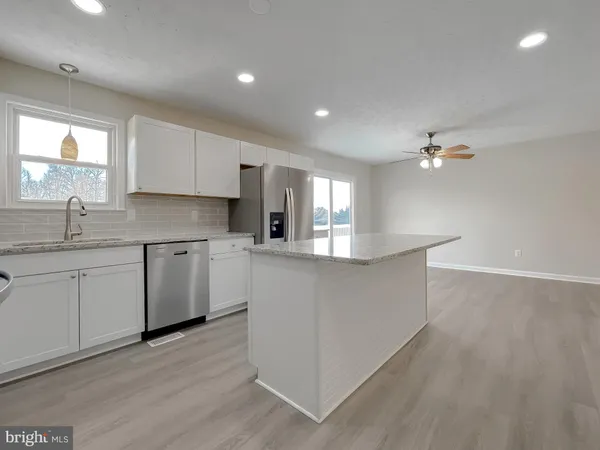 a kitchen with kitchen island a sink dishwasher a stove and white cabinets with wooden floor