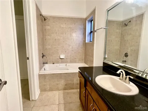 a bathroom with a granite countertop sink a mirror a bathtub and shower