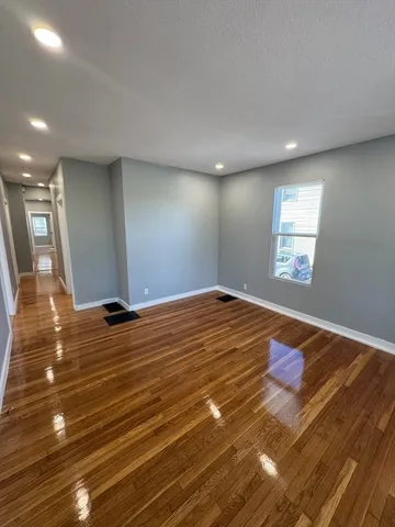 a view of a room has wooden floor and window