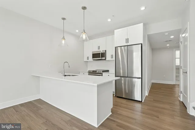 a kitchen with stainless steel appliances a refrigerator a sink and wooden floor