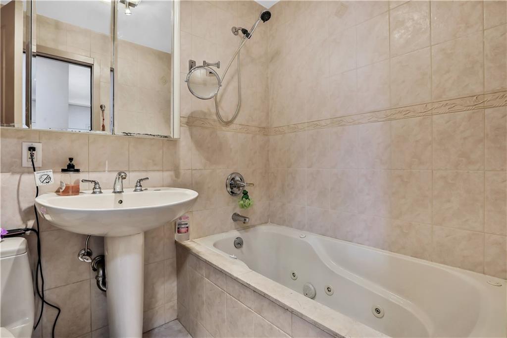 3392 Guider Avenue, Unit 8 Brooklyn, NY 11235 - Photo 12 of 22 a white bath tub sitting next to a white sink and a shower