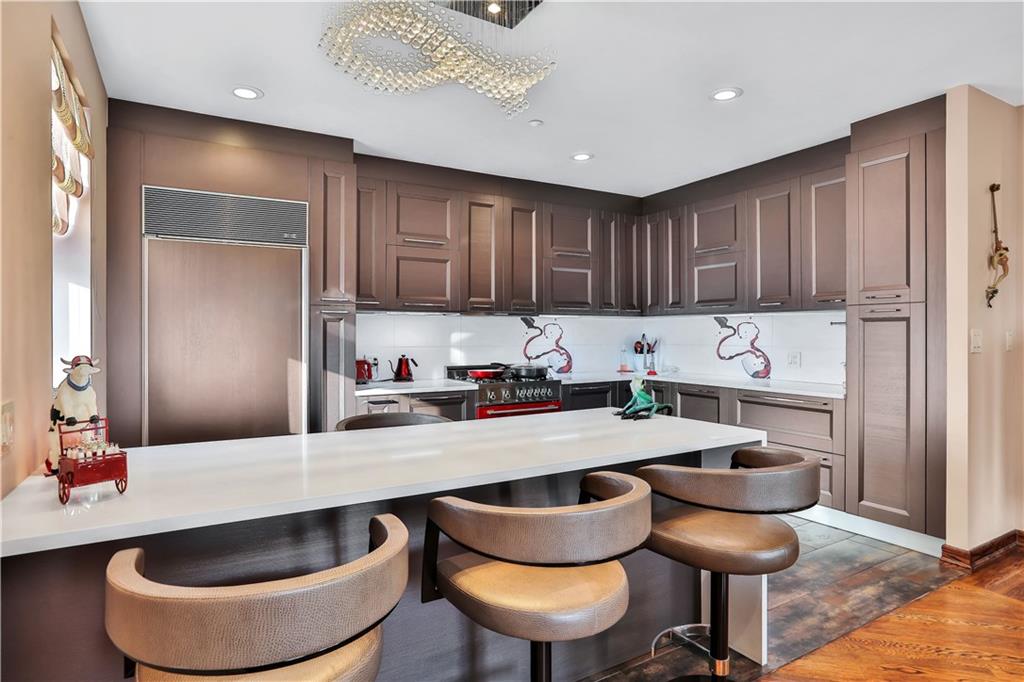3392 Guider Avenue, Unit 8 Brooklyn, NY 11235 - Photo 4 of 22 a kitchen with granite countertop a table chairs stove top oven and cabinets