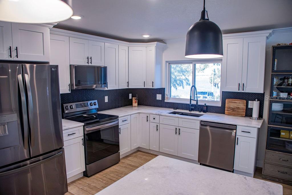 336 Lake Mabel Loop Road Lake Wales, FL 33898 - Photo 22 of 60 a kitchen with stainless steel appliances granite countertop a stove a sink dishwasher a refrigerator and a microwave