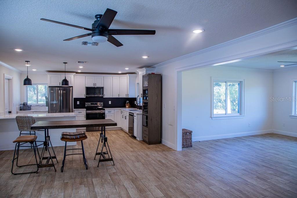 336 Lake Mabel Loop Road Lake Wales, FL 33898 - Photo 24 of 60 a kitchen with stainless steel appliances kitchen island granite countertop a table chairs refrigerator and microwave