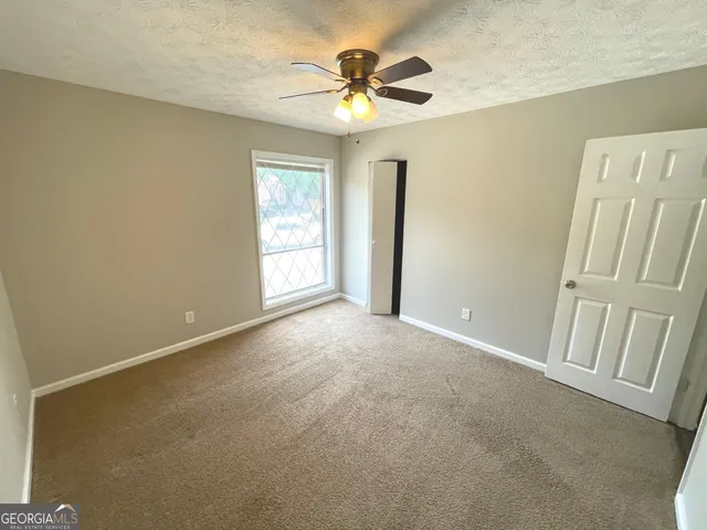 an empty room with windows and fan