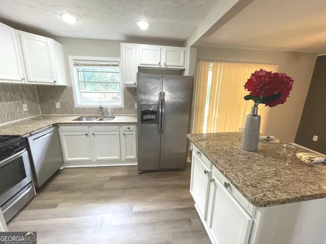 a kitchen with stainless steel appliances granite countertop a sink stove and refrigerator