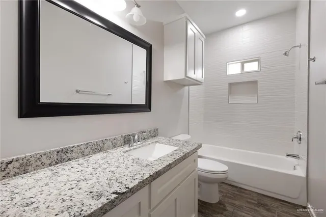 a bathroom with a granite countertop sink a toilet and a bathtub