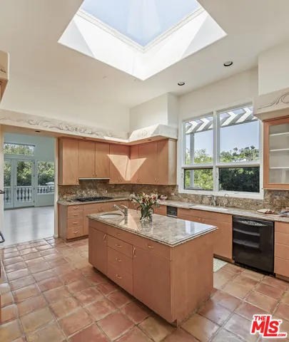 a large kitchen with kitchen island a large counter top space a sink a stove and refrigerator