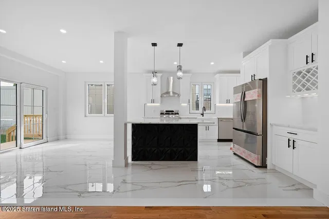 a large white kitchen with stainless steel appliances kitchen island granite countertop a refrigerator and a stove top oven