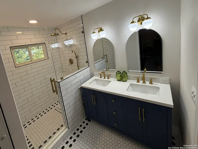 a bathroom with a double vanity sink mirror and shower