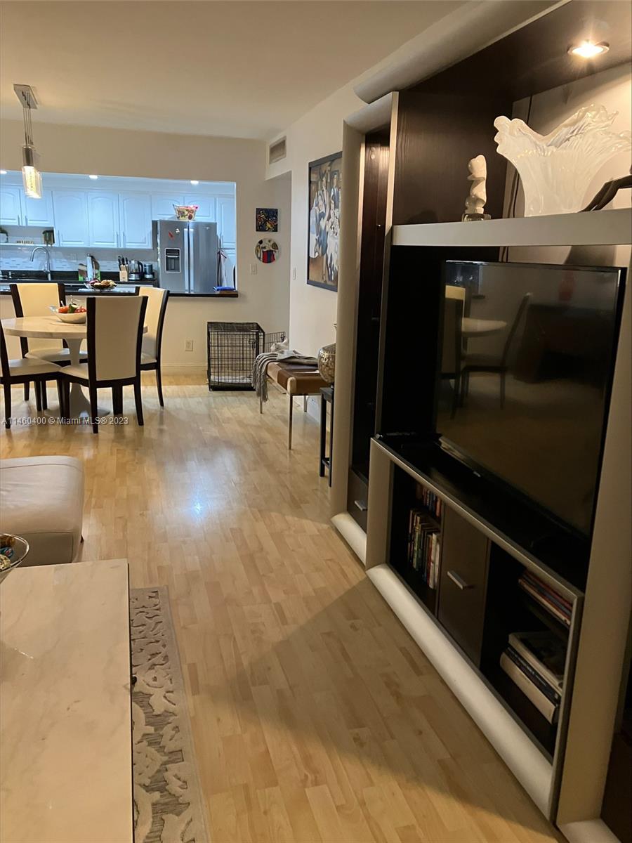 a living room with stainless steel appliances dining table chairs and a refrigerator