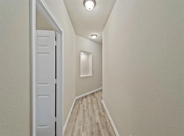 a view of a hallway with wooden floor and closet