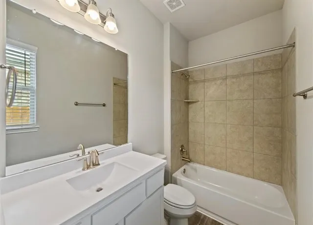 a bathroom with a bathtub shower sink vanity mirror and toilet