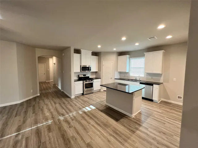 a large kitchen with stainless steel appliances kitchen island granite countertop a stove and a sink