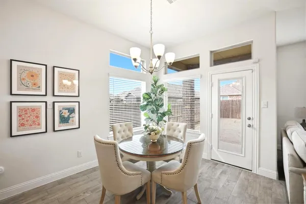 a dining room with wooden floor a chandelier a glass table and chairs