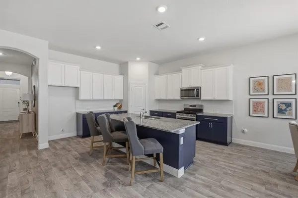 a kitchen with stainless steel appliances granite countertop a stove top oven a refrigerator a sink and dishwasher a oven with wooden floor