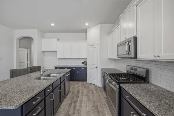 a kitchen with granite countertop stainless steel appliances sink stove microwave and cabinets