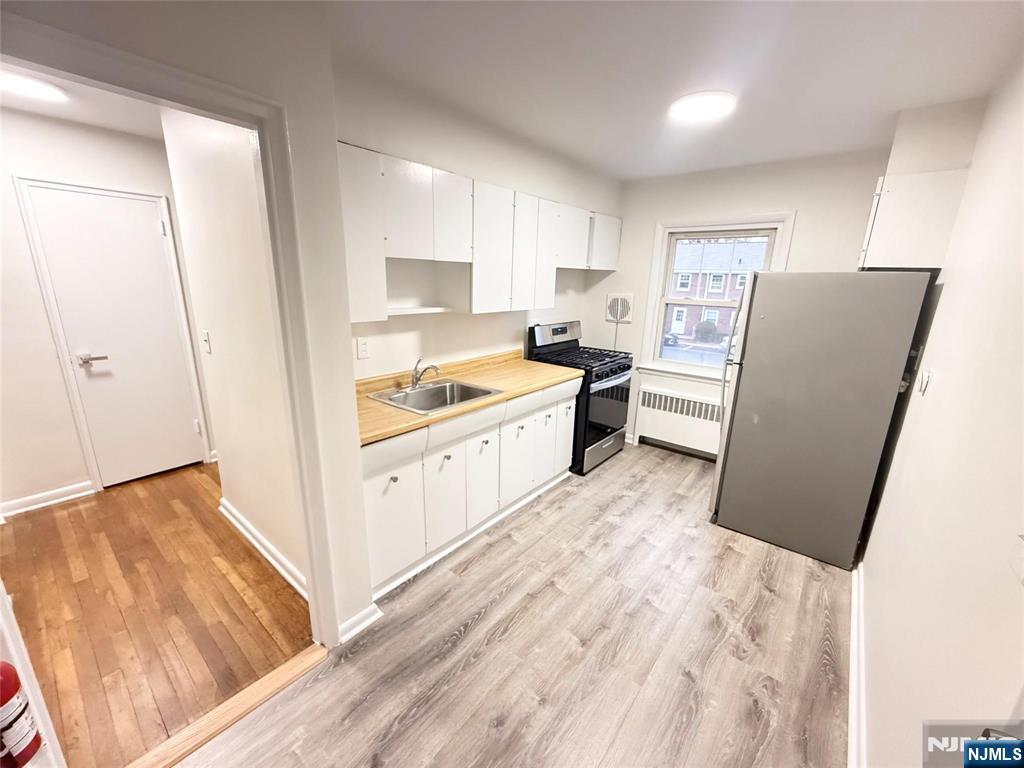 293 Bogert Road River Edge, NJ 07661 - Photo 7 of 14 a kitchen with a refrigerator a stove and white cabinets with wooden floor
