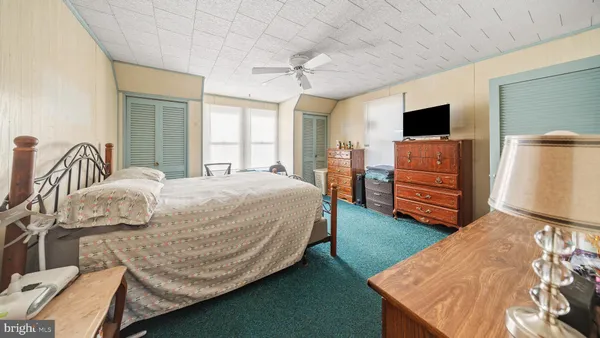 a bedroom with a bed and a flat tv screen on dresser
