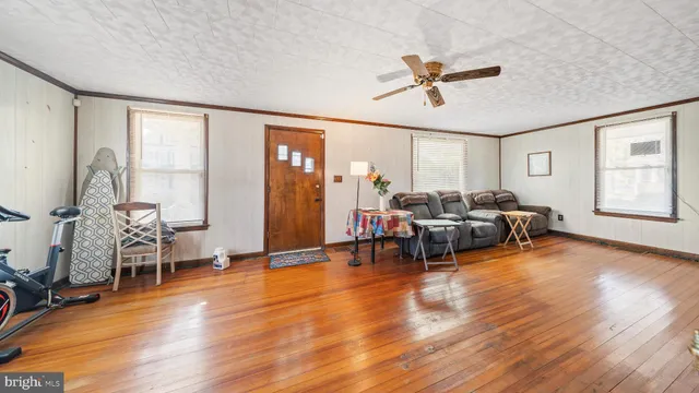 a view of a white house next to a yard with wooden fence