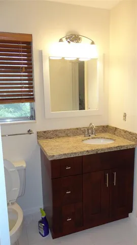 a bathroom with a granite countertop sink and a toilet