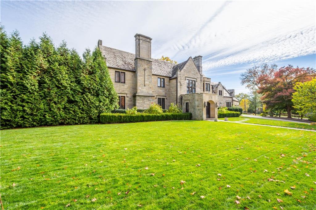 a view of a big house with a big yard and large trees