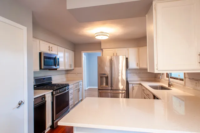 a kitchen with stainless steel appliances granite countertop a sink a stove and a refrigerator