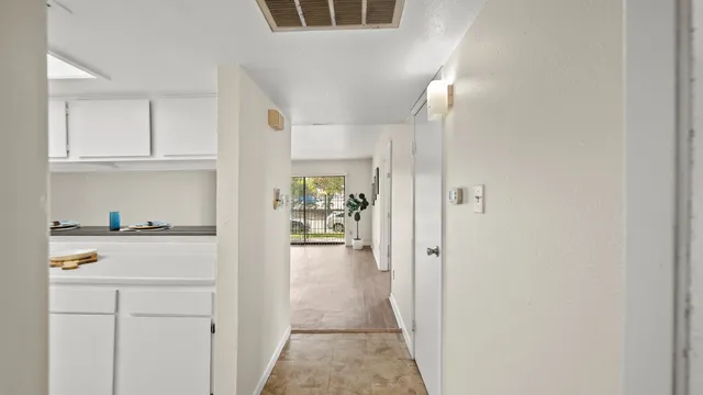 a view of a hallway with white cabinets and wooden floor
