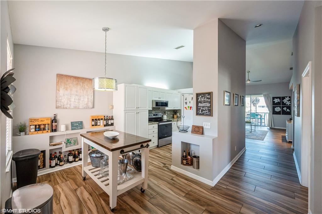 290 Robin Hood Circle, Unit 202 Naples, FL 34104 - Photo 20 of 38 a kitchen with stainless steel appliances granite countertop a stove refrigerator and a view of living room