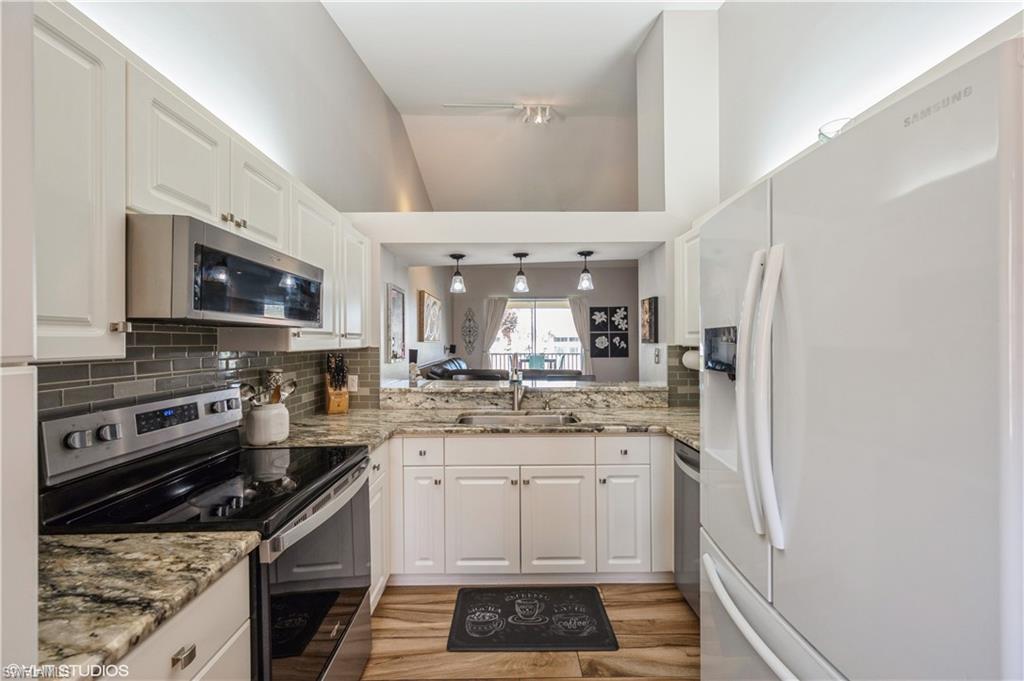 290 Robin Hood Circle, Unit 202 Naples, FL 34104 - Photo 21 of 38 a kitchen with stainless steel appliances granite countertop a stove sink and cabinets