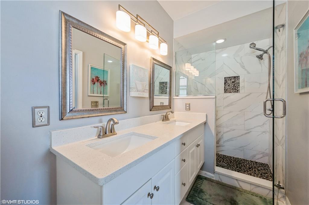 290 Robin Hood Circle, Unit 202 Naples, FL 34104 - Photo 30 of 38 a bathroom with a sink mirror and a shower
