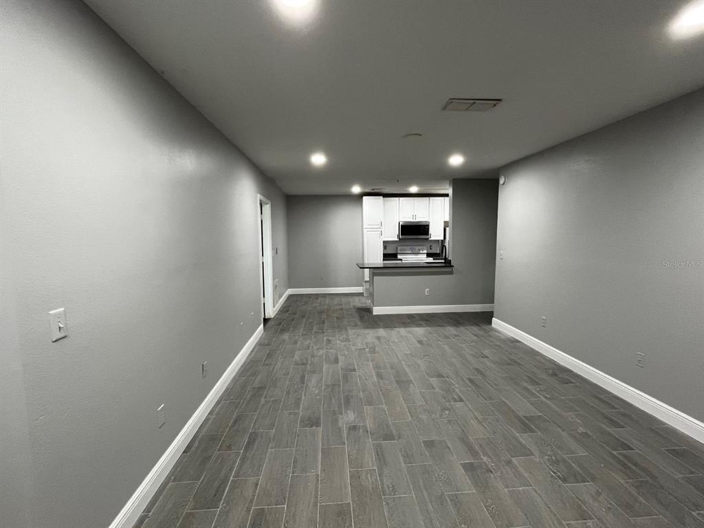 4352 South Kirkman Road, Unit 1203 Orlando, FL 32811 - Photo 2 of 27 Living Room open to kitchen with new flooring and paint