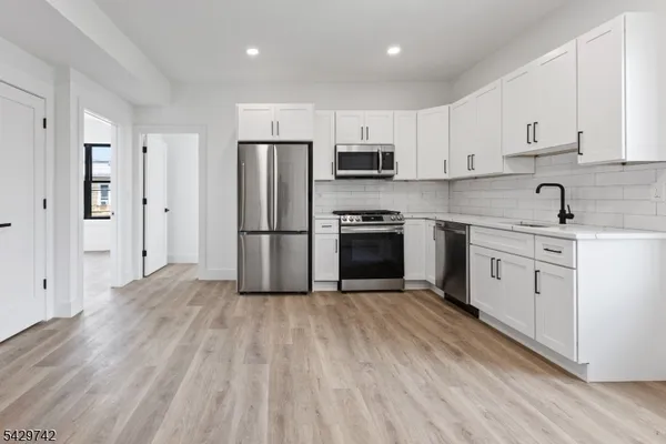 a kitchen with white cabinets stainless steel appliances and wooden floor