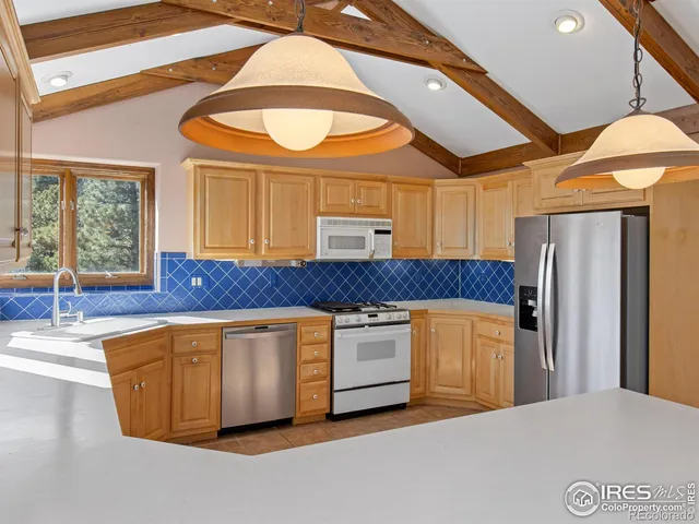 a kitchen with stainless steel appliances a refrigerator a sink a stove and wooden floors
