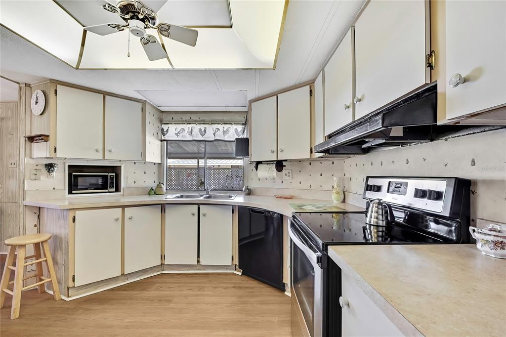 3141 Nantucket Drive Holiday, FL 34690 - Photo 8 of 34 a kitchen with stainless steel appliances granite countertop a sink a stove top oven a chimney and cabinets