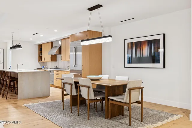 a dining hall with stainless steel appliances kitchen island granite countertop a table chairs and a refrigerator