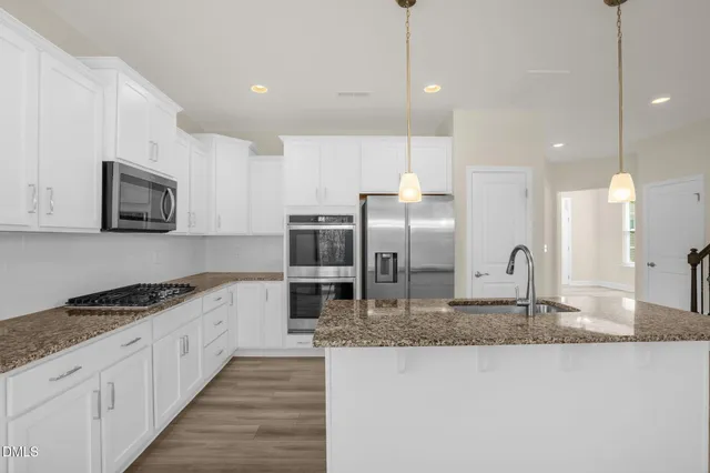 a kitchen with stainless steel appliances granite countertop a sink a stove and a refrigerator