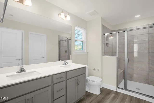 a bathroom with a double vanity sink toilet mirror and shower