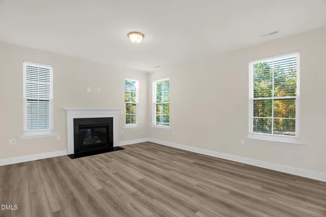 an empty room with windows and fireplace