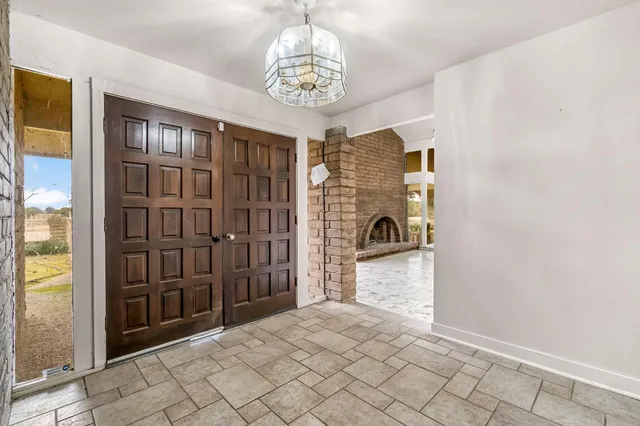 a view of a livingroom with a fireplace a chandelier and windows