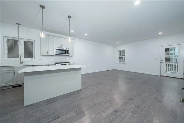 a kitchen with kitchen island white cabinets and wooden floor