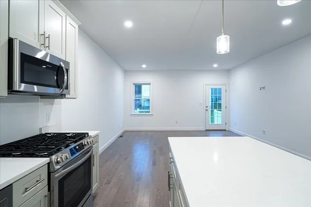 a kitchen with granite countertop a stove and a wooden floor