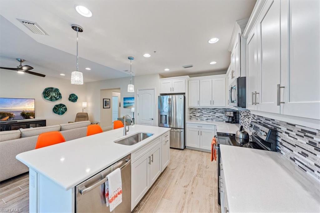 6934 Avalon Circle, Unit 402 Naples, FL 34112 - Photo 11 of 28 a large kitchen with stainless steel appliances a stove a refrigerator a oven a sink with island and chairs